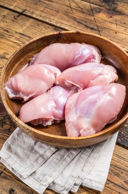 Fresh Chicken thigh meat, Raw Boneless and skinless fillet in a wooden plate. Wooden background. Top view.