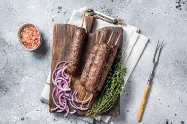 Grilled kofta kofte shish kebab from mince lamb and beef meat on Skewer. Gray background. Top view.