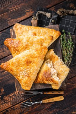 Tavuk ve peynirli fırında samosa, samsa turtası. Ahşap arka plan. Üst görünüm.