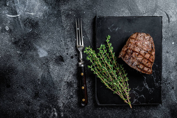 Grilled Rump steak with spices, cooked beef meat. Black background. Top view. Copy space.