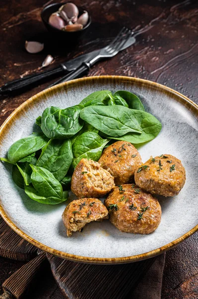 Fish Cakes or Fish balls with tuna and spinach in a plate. Dark background. Top view.