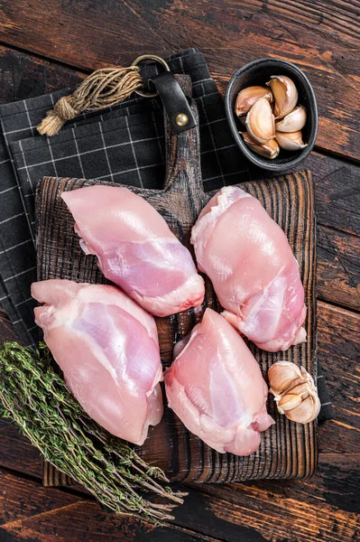 Chicken thigh fillet, Raw Boneless and skinless meat on a cutting board. Wooden background. Top view.