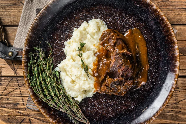 Beef cheeks stewed in red wine sauce with mashed potatoes. Wooden background. Top view.
