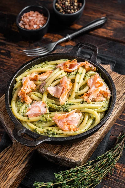 Salmon Bucatini pasta with creamy spinach sauce and fish fillet. Wooden background. Top view.