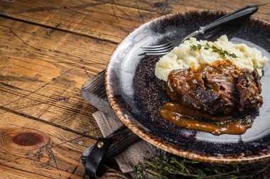 Beef cheeks stewed in red wine sauce with mashed potatoes. Wooden background. Top view. Copy space.