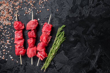 Shashlik raw beef veal shish kebab, Meat with herbs on Skewers. Black background. Top view. Copy space.