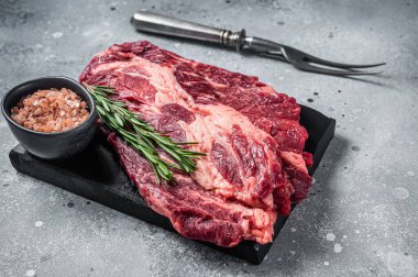 Baharat ve otlarla ızgara ve pişirilmemiş sığır eti rulo biftekleri. Gri arka plan. Üst görünüm.