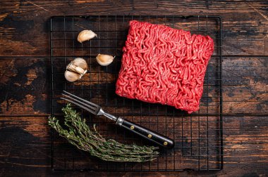 Mincemeat, Forcemeat. Raw minced beef meat on a kitchen table with herbs. Wooden background. Top view.