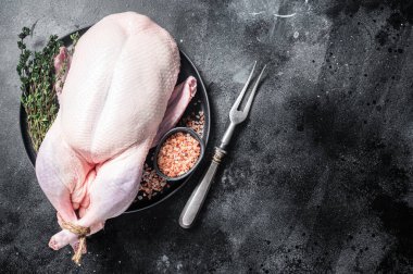 Organic eco uncooked whole duck with thyme and salt. Black background. Top view. Copy space.