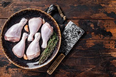 Chicken drumsticks legs, raw poultry meat on butcher board. Wooden background. Top view. Copy space.