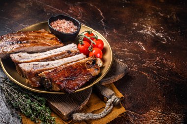 Chopped BBQ pork ribs on a plate with herbs. Dark background. Top view. Copy space.
