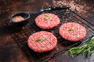 Raw burger cutlet from beef meat with spices and rosemary ready for cooking. Dark background. Top view.