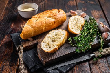 Ahşap kesme tahtasının üzerinde otlu ve tereyağlı sarımsaklı ekmek. Ahşap arka plan. Üst görünüm.