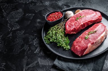 Dry aged Raw top blade flat Iron beef meat steaks. Black background. Top View. Copy space.