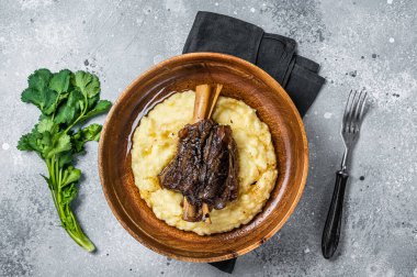 Braised lamb shank on the mashed potato in a plate. Gray background. Top view.