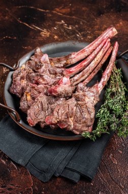 BBQ Grilled lamb chop steak, mutton rib cutlet in steel tray with thyme. Dark background. Top view.