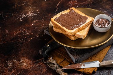 Stack of Toasts with chocolate Hazelnut cream in plate. Dark background. Top view. Copy space.