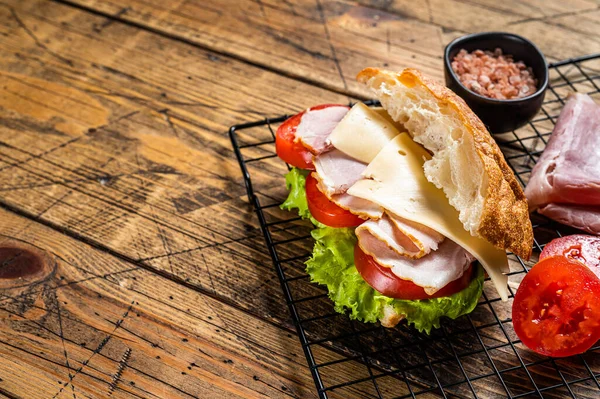 Sub sandwich with ham, cheese, tomato and Lettuce. Wooden background. Top view. Copy space.