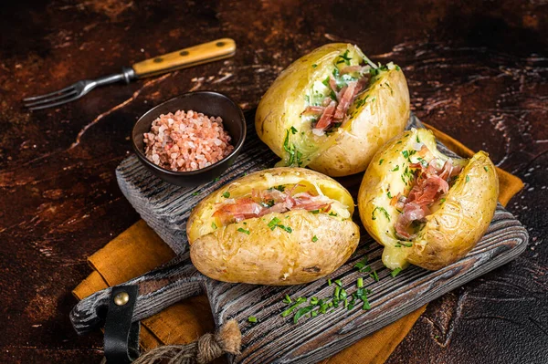 Jacket potatoes baked with cheese, herbs and butter. Dark background. Top view.