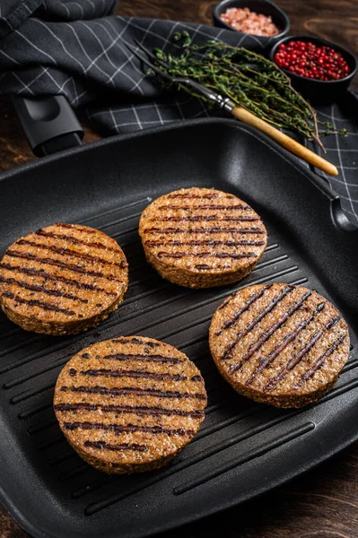 Grilled Vegetarian plant based meat burger patties, vegan cutlets on grill skillet. Wooden background. Top view.