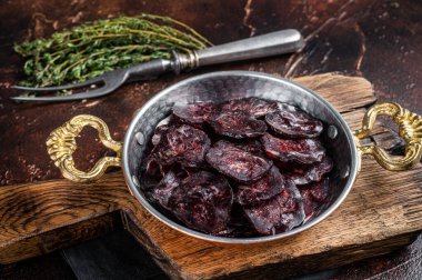 Ev yapımı geyik eti sosisi. Tavada otlar var. Karanlık arka plan. Üst görünüm.