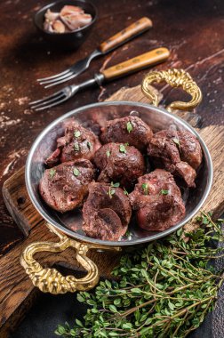 Kızarmış sığır böbreği, tavada sakatat eti ve şifalı otlar. Karanlık arka plan. Üst görünüm.