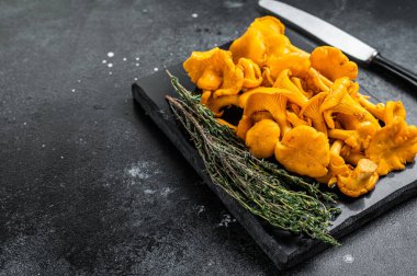 Mermer bir tahtanın üzerinde çiğ Chanterelles mantarı. Siyah arka plan. Üst Manzara. Boşluğu kopyala.