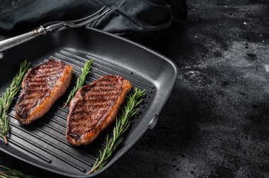 Grilled Top sirloin beef steak or brazilian Picanha, roasted meat on grill pan. Black background. Top view. Copy space.