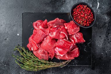 Mermer tahtada Gulaş için çiğ kırmızı et. Siyah arka plan. Üst görünüm.