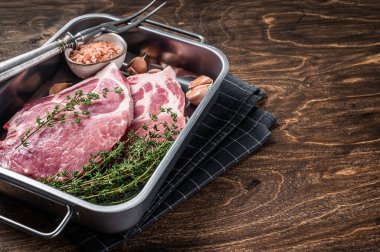 Mutfak tepsisinde taze et ve tuzlu kekik ile çiğ domuz bifteği. Ahşap arka plan. Üst Manzara. Boşluğu kopyala.