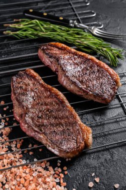 Barbekü ızgara biftek veya sığır filetosu bifteği, ızgarada kızarmış et. Siyah arka plan. Üst görünüm.