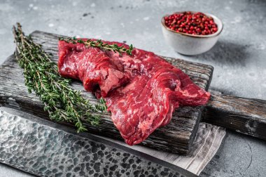 Skirt or Machete beef steak, raw meat with herbs and spices. Gray background. Top view.