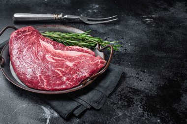 Biberiyeli çelik tepside çiğ sığır eti bifteği. Siyah arka plan. Üst Manzara. Boşluğu kopyala.