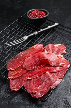 Dried sliced basturma, cured beef meat ready for eat. Black background. Top view.
