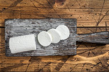 Sliced Soft Goat cheese on a cutting board. Wooden background. Top view.