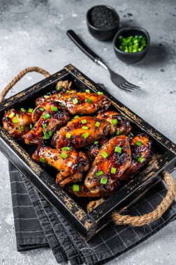 BBQ Chicken wings in Teriyaki sauce with black sesame in a tray. Gray background. Top view.