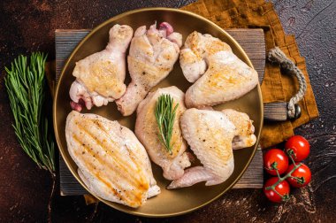 Tabakta kızarmış tavuk eti parçaları çeşitleri. Baget, göğüs filetosu, kanat, but. Karanlık arka plan. Üst görünüm.