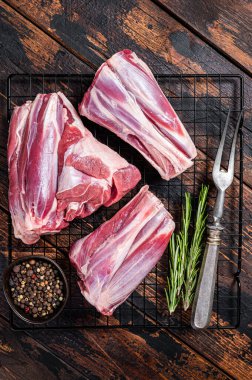 Raw lamb shanks with herbs and spices ready for cooking. Wooden background. Top view.