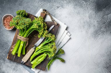 Fresh bunch of Broccolini sprouts on cutting board ready for cookining. White background. Top view. Copy space.