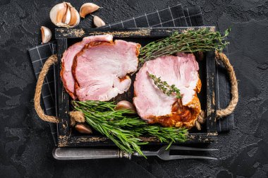 Dilimlenmiş tütsülenmiş tavla, domuz eti ve otlar. Siyah arka plan. Üst görünüm.