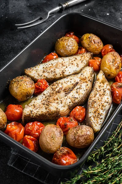 Kızarmış halibut balığı bifteği, domates ve patates. Siyah arka plan. Üst görünüm.