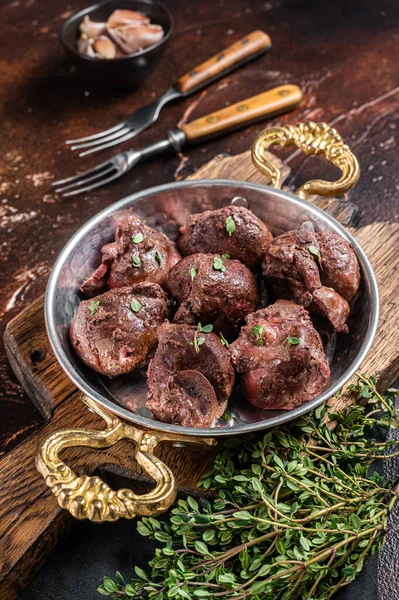 Kızarmış sığır böbreği, tavada sakatat eti ve şifalı otlar. Karanlık arka plan. Üst görünüm.