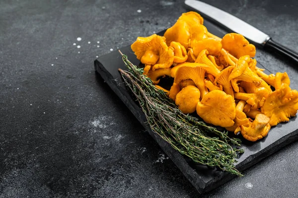 Mermer bir tahtanın üzerinde çiğ Chanterelles mantarı. Siyah arka plan. Üst Manzara. Boşluğu kopyala.
