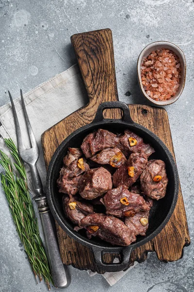 Grilled Sauteed Diced Beef in a skillet with garlic. Gray background. Top view.