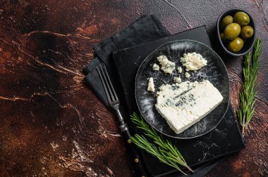 Çelik bir tabakta zeytin ve bitkilerle rokfor peyniri. Karanlık arka plan. Üst Manzara. Boşluğu kopyala.