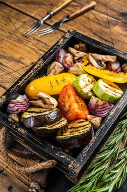 Assortment of grilled Vegetables in a wooden box, bell pepper, zucchini, eggplant, onion and tomato. Wooden background. Top view.