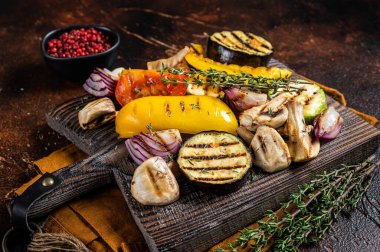 Summer BBQ with grilled Vegetables, bell pepper, zucchini, eggplant, onion and tomato on a wooden board. Dark background. Top view.