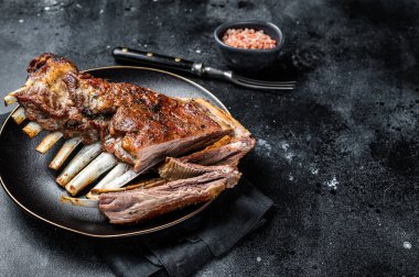 Roasted Rack of lamb ribs, mutton spareribs, sliced meat on plate. Black background. Top view. Copy space.