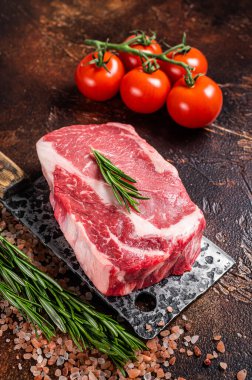Pişmemiş çiğ kaburga bifteği, kasap baltası ve şifalı biftek. Karanlık arka plan. Üst görünüm.