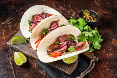 Carne Asada Tacos with grilled steak, green sauce, jalapenos and onion, Mexican food. Dark background. top view.